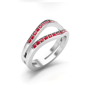 May include: A silver ring with a split band design. The band is set with a row of red gemstones.