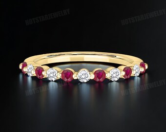 May include: A delicate gold band ring with alternating red rubies and clear diamonds. The ring is set in a simple, elegant style.
