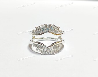 Puede incluir: Un protector de anillo plateado con un diseño en forma de V. El protector de anillo está incrustado con pequeñas piedras preciosas transparentes. El anillo está marcado con "925".