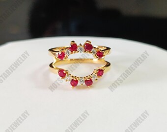 May include: Gold ring with a double band design. The top band features a row of red gemstones and smaller clear gemstones. The bottom band features a row of red gemstones.
