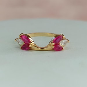 Puede incluir: Anillo de oro con un diseño de banda dividida, con piedras de forma marquesa rojas y transparentes.