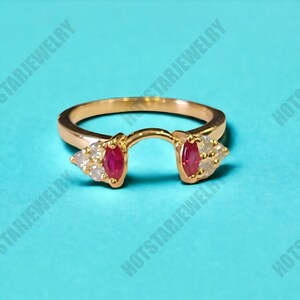 May include: A gold ring with two red ruby stones and small white diamonds on each side. The ring is open in the back and designed to hold a separate stone.