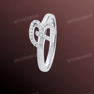 May include: A silver ring with a diamond-encrusted letter 'B' on the band.