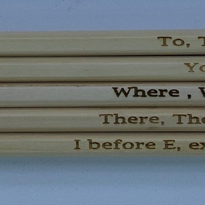 May include: Five wooden pencils with eraser tops and engraved text. The pencils read: "To, Too & Two", "Your & You're", "Where, Were & We're", "There, Their & They're", and "I before E, except after C".
