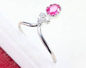 Puede incluir: Un anillo de tono plateado con una banda en forma de V que se divide en dos puntas. Una punta está rematada con una piedra preciosa rosa vibrante de corte ovalado, mientras que la otra está acentuada con un grupo de tres piedras blancas redondas.