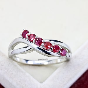 Peut inclure: Une bague en argent avec une bande torsadée ornée de sept pierres de rubis rouges.