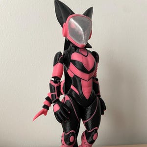 May include: A 3D-printed figurine of a humanoid character in a futuristic suit. The figure is primarily black and pink, with a helmet and accents in a lighter pink. The figure is standing on a black circular base.