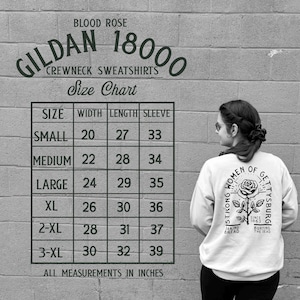 May include: A white Gildan 18000 crewneck sweatshirt with a rose graphic and text. The size chart shows measurements in inches, with a small size having a 20-inch width and 27-inch length. The text reads "Strong Women of Gettysburg."