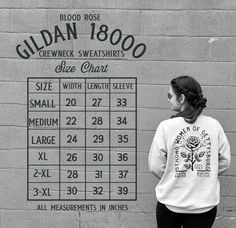 May include: A white Gildan 18000 crewneck sweatshirt with a rose graphic and text. The size chart shows measurements in inches, with a small size having a 20-inch width and 27-inch length. The text reads "Strong Women of Gettysburg."