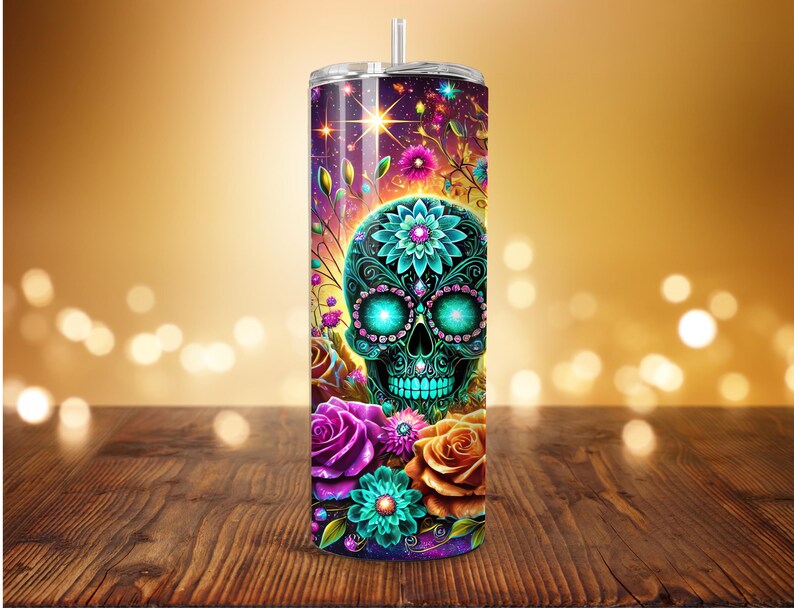 May include: A tall, stainless steel tumbler with a colorful Day of the Dead design. The design features a teal skull with floral accents, surrounded by roses and other flowers in shades of purple, orange, and teal. The background is a gradient of purple and gold.