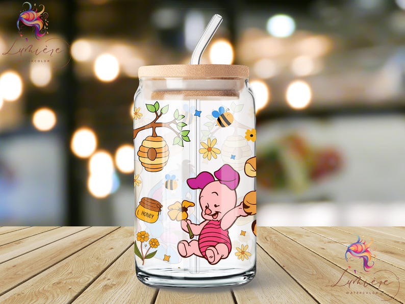 May include: A clear glass jar with a straw and a wooden lid. The jar has a colorful design featuring a cartoon pig, honeycombs, bees, and flowers. The text "Honey" is printed on the jar.