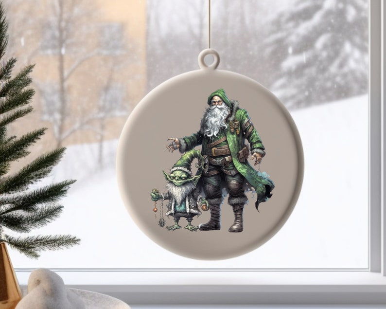 Op de afbeelding: Een ronde, witte kerstbal met een groen geklede kerstman en een groene kobold die een reeks ornamenten vasthoudt. De kerstbal is versierd met een beige achtergrond.