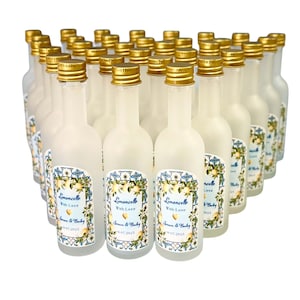 May include: A collection of small, frosted glass bottles with gold-colored caps. Each bottle has a label with the text "Limoncello With Love" and a floral design. The labels also include names and a date.