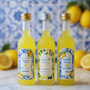 May include: Three small bottles of limoncello with gold and silver caps. Each bottle has a unique label with text and lemon illustrations. The labels read "Limoncello Made with Love" and "Limoncello With Love" with names and dates.