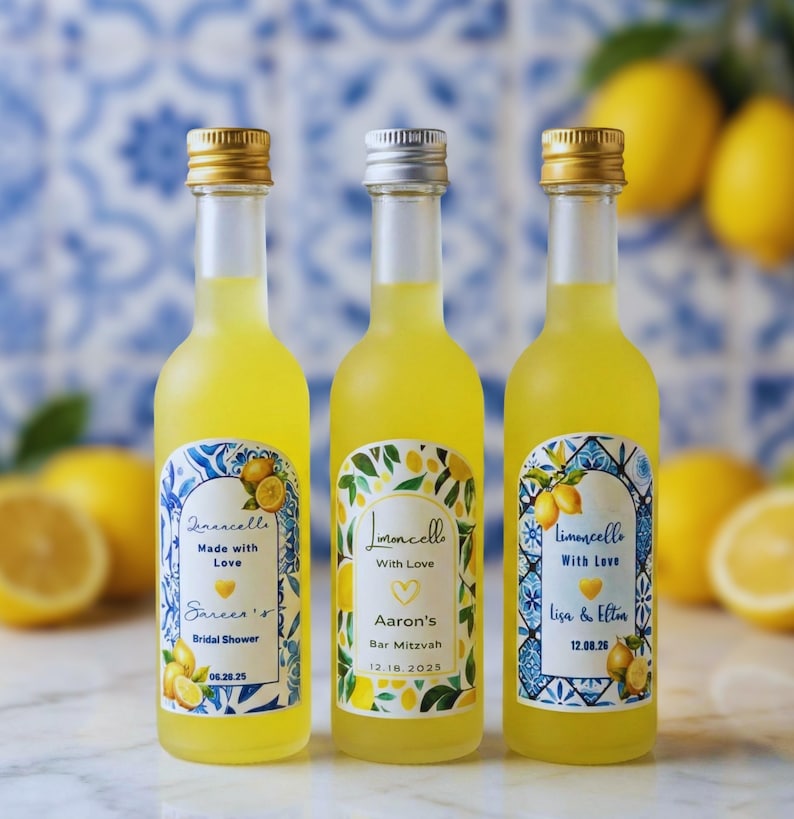 May include: Three small bottles of limoncello with gold and silver caps. Each bottle has a unique label with text and lemon illustrations. The labels read "Limoncello Made with Love" and "Limoncello With Love" with names and dates.