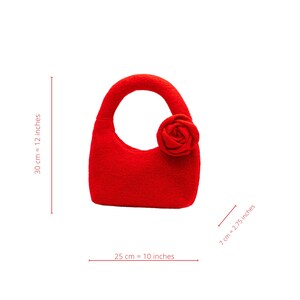 May include: A vibrant red handbag with a rounded handle and a decorative rose. The bag is approximately 10 inches wide, 12 inches tall, and 2.75 inches deep. The bag is made of a soft material and is suitable for carrying small items.