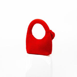 May include: A small, bright red handbag with a rounded handle and a decorative knot on the side. The bag is made of a soft material and has a simple, elegant design. The bag is suitable for carrying small items.