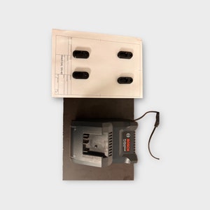 Op de afbeelding: Een zwarte Bosch GAL 18V-40 lader met een zwart stroomkabel. De lader staat op een zwart oppervlak. De lader heeft een label met de tekst "Bosch Professional".