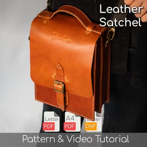 Op de afbeelding: Een bruine leren tas met een handvat aan de bovenkant en een gespsluiting. De tas heeft een flap en een schouderriem. De tekst "Leather Satchel" is zichtbaar. De afbeelding bevat ook de tekst "Pattern & Video Tutorial".