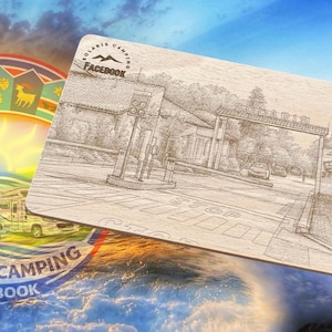 Könnte beinhalten: Ein Holzschild mit einer detaillierten Skizze eines Campingplatz-Eingangs, mit dem Text "SOLARIS CAMPING FACEBOOK". Ein farbenfrohes kreisförmiges Logo mit Wohnmobilen und einer Sonne im Hintergrund.