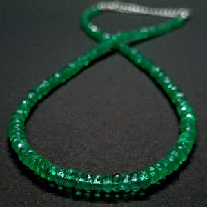May include: A necklace composed of small, faceted, vibrant green gemstone beads arranged in a circular pattern. The strand features a metallic silver-toned extender chain at the top, providing an adjustable closure for the circular beaded necklace.
