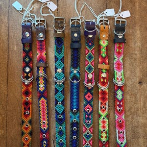 May include: Seven woven fabric dog collars with numbered labels from 1 to 7. Each collar features a unique geometric pattern in vibrant colors, including red, blue, green, purple, and pink. They have metal buckles, D-rings, and eyelets.