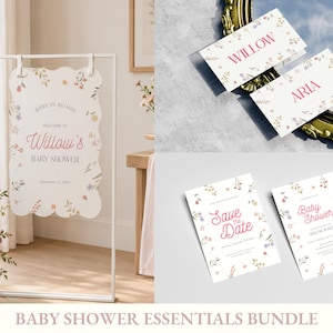 Puede incluir: Un conjunto de papelería para baby shower que incluye un letrero de bienvenida festoneado en un soporte de metal blanco, dos tarjetas de lugar plegadas con los nombres Willow y Aria, y dos tarjetas rectangulares con motivos florales.
