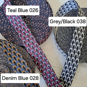 Op de afbeelding: Close-up van drie spoelen met patroonlint. De linten zijn in de kleuren teal blauw, grijs/zwart en denim blauw. Elk lint heeft een uniek geometrisch ontwerp. De tekst op de afbeelding luidt "Teal Blue 026", "Grey/Black 038" en "Denim Blue 028".