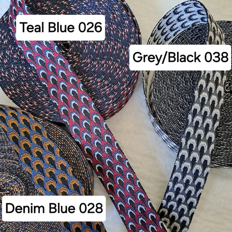 Op de afbeelding: Close-up van drie spoelen met patroonlint. De linten zijn in de kleuren teal blauw, grijs/zwart en denim blauw. Elk lint heeft een uniek geometrisch ontwerp. De tekst op de afbeelding luidt "Teal Blue 026", "Grey/Black 038" en "Denim Blue 028".