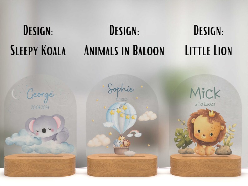 May include: Three personalised night lights with different designs. The first features a sleeping koala, the second has animals in a hot air balloon, and the third has a lion. Each light has a wooden base and a clear acrylic panel with a name and date.