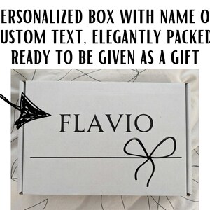 May include: A white gift box with a black ribbon and bow. The box is personalised with the name "FLAVIO" printed in black.