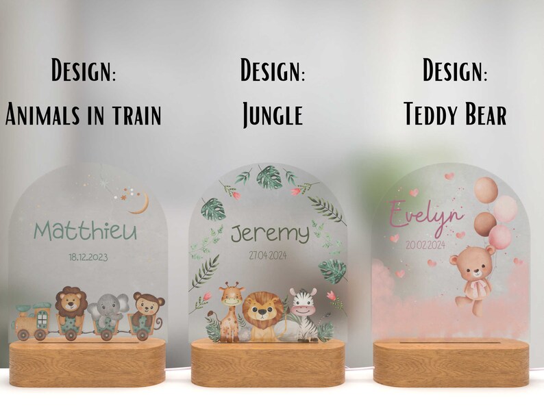 May include: Three personalised night lights with different designs. The first features a train with animals, the second has a jungle theme, and the third has a teddy bear with balloons. Each light has a wooden base and a frosted glass panel with a name and date.
