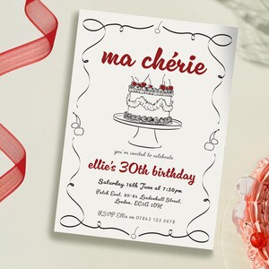 Op de afbeelding: Een witte uitnodigingskaart met zwarte kalligrafie en rode tekst. De tekst luidt "ma chérie" en "ellie's 30th birthday". De uitnodiging bevat details voor het verjaardagsfeest, inclusief de datum, tijd en locatie.