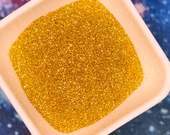 May include: A small white square dish filled with fine gold glitter.
