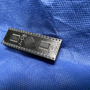 May include: A rectangular black circuit board with the text "J-CIA" and several integrated circuits. The board has numerous small silver components and is set against a blue background.