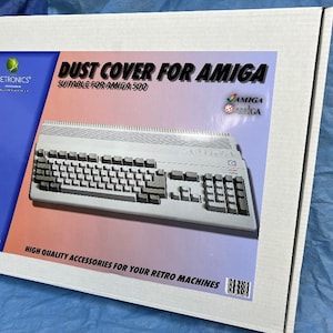May include: A white cardboard box with a product image of a retro computer keyboard. The box is labelled "DUST COVER FOR AMIGA" and "SUITABLE FOR AMIGA 500". The Retronics logo and the text "HIGH QUALITY ACCESSORIES FOR YOUR RETRO MACHINES" are also visible.