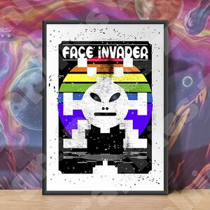 Könnte beinhalten: Ein gerahmter Kunstdruck mit einem Retro-Alien-Grafik und dem Text "FACE INVADER". Der Alien ist pixelig mit einem Regenbogenverlauf, vor einem schwarzen Hintergrund mit einem Used-Effekt. Der Hintergrund ist eine farbenfrohe Weltraumszene.