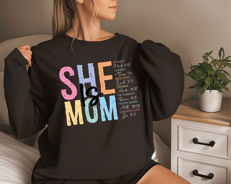 May include: Black sweatshirt with the text "SHE IS MOM" in rainbow colors. The text is surrounded by a list of words and bible verses describing the qualities of a mother.