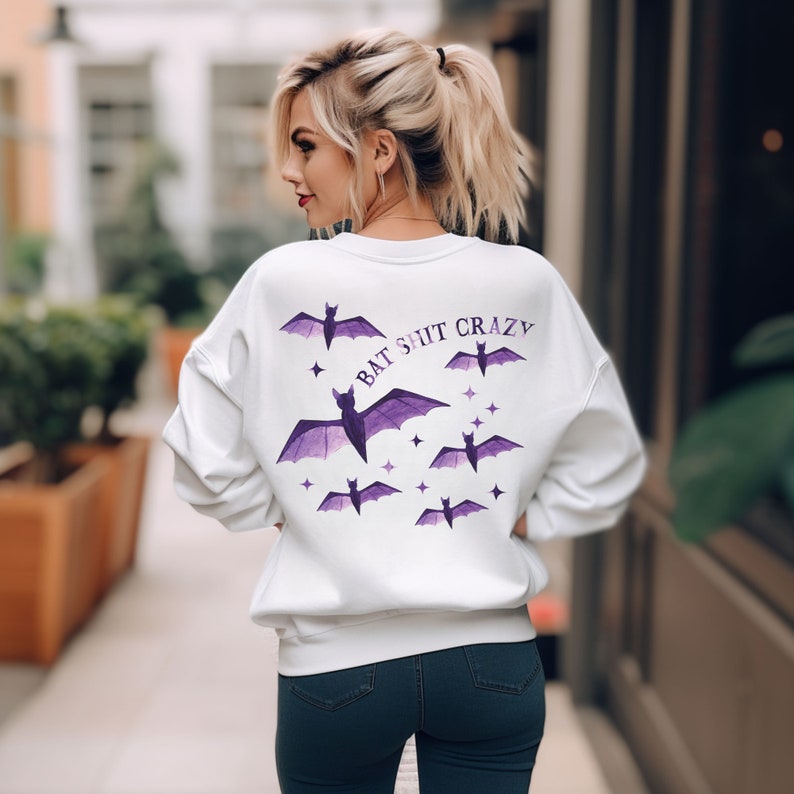 May include: White sweatshirt with a purple bat design and the text "BAT SHIT CRAZY" on the back.