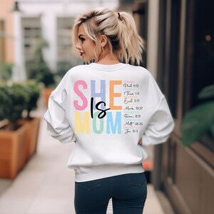 May include: White sweatshirt with the text "SHE IS MOM" in rainbow colors. The text is accompanied by bible verses describing the qualities of a mother.