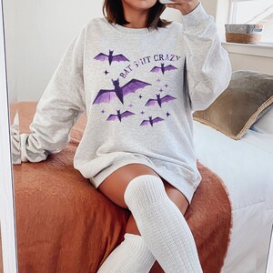 May include: A gray sweatshirt with a purple bat graphic and the text "Bat 3ut Crazy".