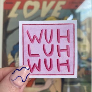 May include: A pink square sticker with the words "WUH LUH WUH" in a darker pink. The sticker is held up in front of a vintage comic book cover that says "TEEN-AGE LOVE".