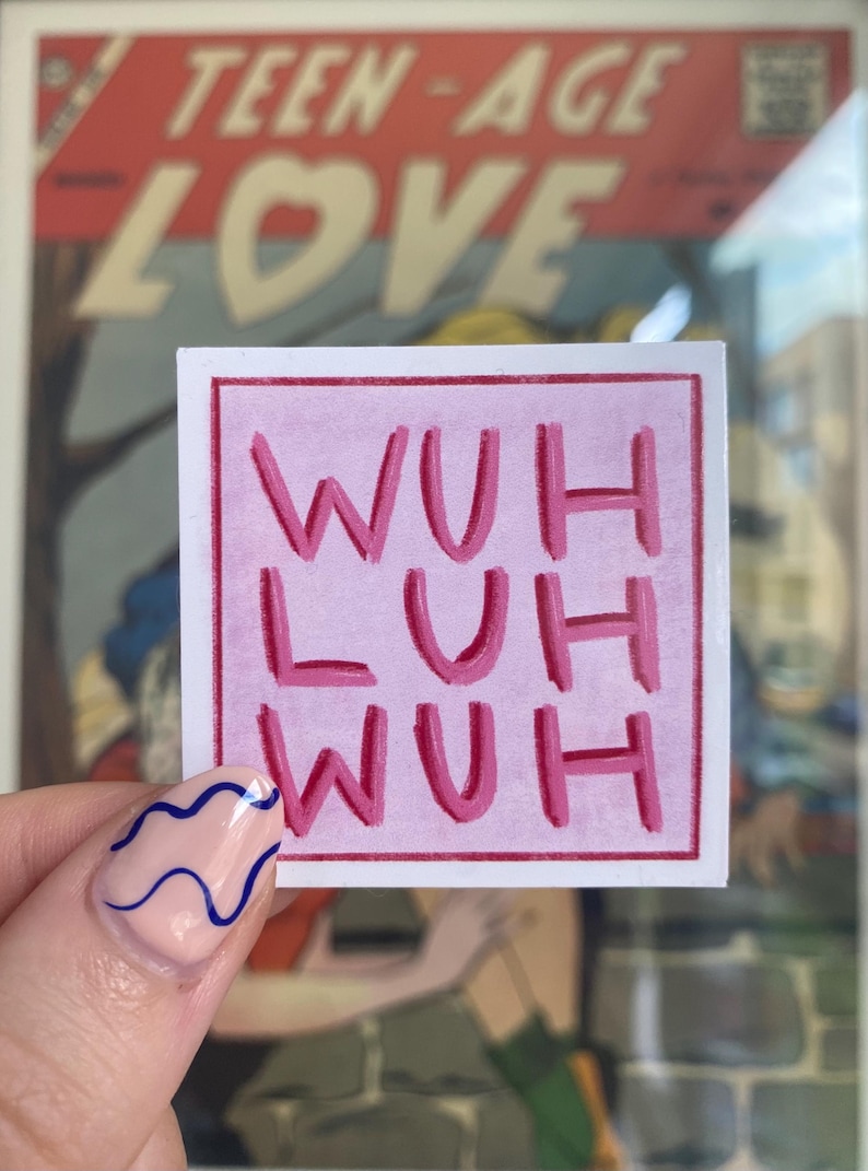 May include: A pink square sticker with the words "WUH LUH WUH" in a darker pink. The sticker is held up in front of a vintage comic book cover that says "TEEN-AGE LOVE".