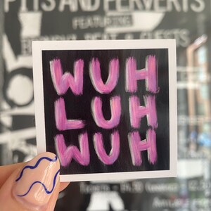 May include: Square sticker with the text "WUH LUH WUH" in pink brushstrokes on a black background. The sticker is held up by a hand with a light pink nail with blue wavy lines.