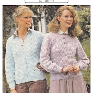 以下が含まれることがあります： 2人の女性が、薄い青とラベンダー色の「ファン＆フェザーパターン」のニットカーディガンを着ています。「DK / 8 Ply 32 - 38 ins」というテキストが女性たちの頭上に表示されています。