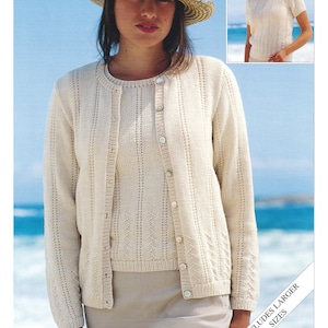 May include: A white knitted cardigan and matching top with a button closure. The cardigan has a delicate openwork pattern. The model is wearing a straw hat and a skirt. The text "DK / 8 PLY 32 TO 54 INS" and "INCLUDES LARGER SIZES" is visible on the image.