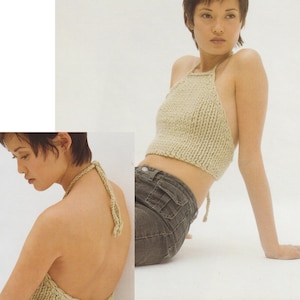 May include: A light beige halter top with thin straps. The top is knitted and has a loose fit. The model is wearing the top with dark denim jeans.