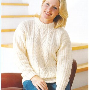 Könnte beinhalten: Ein weißer Strickpullover mit Zopfmuster. Der Pullover hat einen runden Ausschnitt und lange Ärmel. Der Pullover ist in den Größen 30-42 Zoll erhältlich.