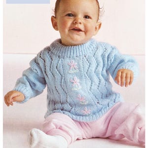 May include: A light blue knitted baby sweater with a cable stitch pattern and embroidered flowers. The sweater is for a baby with a 14 to 20 inch chest and is suitable for premature babies to 12 months old. The yarn is 4 ply fine yarn.