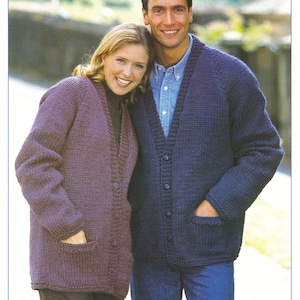 May include: Two people wearing chunky knit cardigans with pockets. The cardigan on the left is purple and the cardigan on the right is blue. The text "BRAEMAR Chunky / Bulky 30-52 in 76-132 cm" is at the bottom of the image.